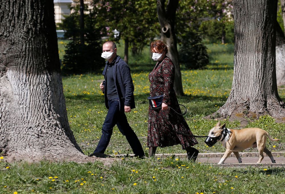 People wearing protective face masks walk with a dog across a park, amid the coronavirus disease (Covid-19) outbreak in Kiev April 30, 2020. u00e2u20acu201d Reuters pic