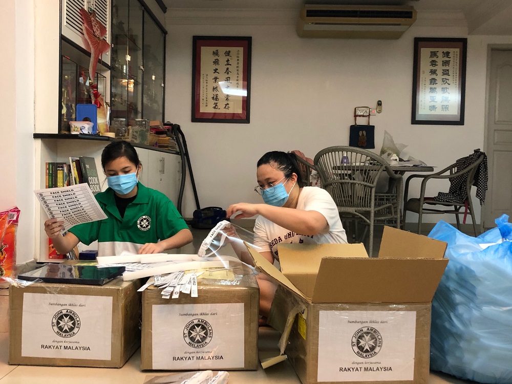 Volunteers Shannon Trisha Lee (left) and Sabrina James producing face shields in Keningau, Sabah after receiving the materials. — Picture courtesy of SJAM