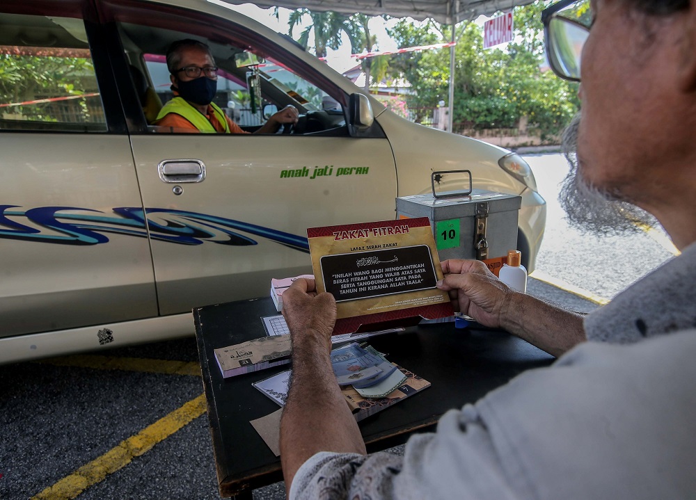 A muslim man pays his tithe (zakat fitrah) at a drive-through collection centre at Masjid Sultan Yussuf Rapat Setia in Ipoh May 12, 2020. u00e2u20acu201d Picture by Farhan Najib