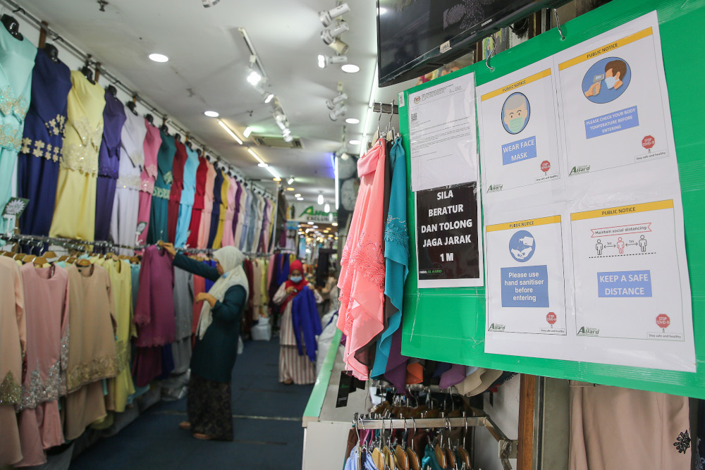 Notices detailing standard operating procedures are displayed at the entrance of the store as women shop for clothes ahead of Hari Raya Aidilfitri in Kuala Lumpur May 22, 2020. u00e2u20acu201d Picture by Yusof Mat Isa