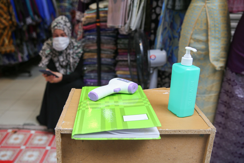 A digital thermometer used to detect body temperatures, hand sanitiser and log book are pictured at the entrance of the store at Jalan Tunku Abdul Rahman in Kuala Lumpur May 22, 2020. u00e2u20acu201d Picture by Yusof Mat Isa