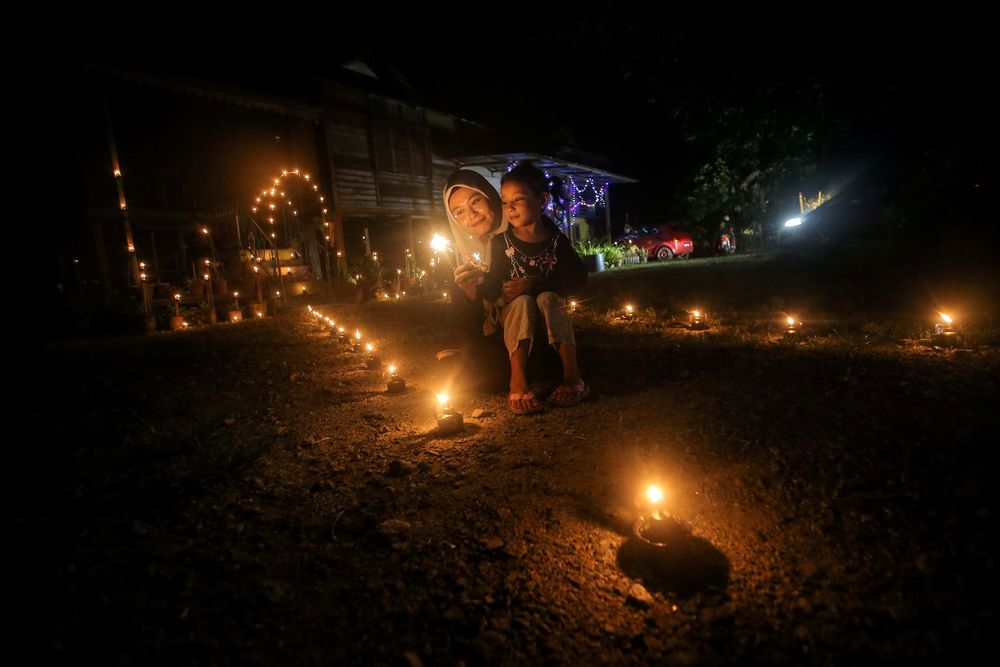 Nur Maisarah Othman, 33 and son, Nur Qaseh Zullaikha Muazri admiring the pelita panjut put up at Kampung Ribu.