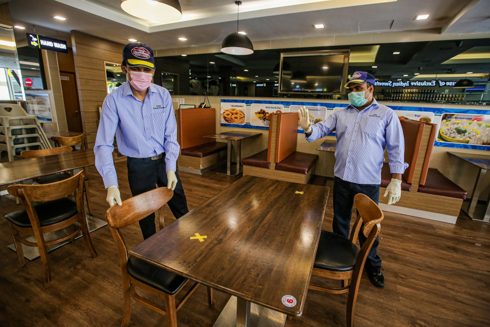 Adyar Ananda Bhavan staff arrange tables to comply with social distancing seating guidelines in Masjid India May 4, 2020. — Picture by Hari Anggara 