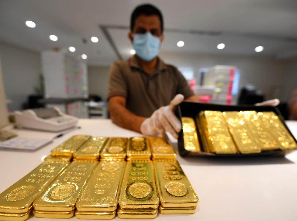 A jeweller showcases bars of gold at a shop at the Dubai Gold Souk in the Gulf emirate May 13, 2020, as markets re-open amidst an easing of pandemic restrictions. u00e2u20acu201d AFP pic 