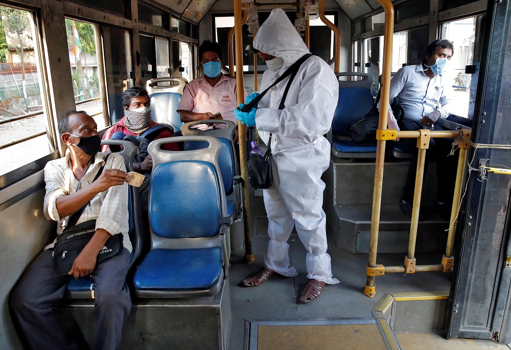 A bus conductor wearing a protective gear issues tickets to passengers maintaining safe social distance on the bus in Kolkata May 14, 2020. u00e2u20acu2022 Reuters pic