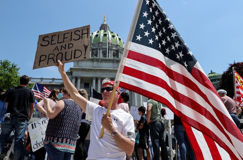 A supporter of US President Donald Trump holds a US flag during a protest against coronavirus disease restrictions outside the Pennsylvania State Capitol Building in Harrisburg, Pennsylvania May 15, 2020. u00e2u20acu2022 Reuters pic 