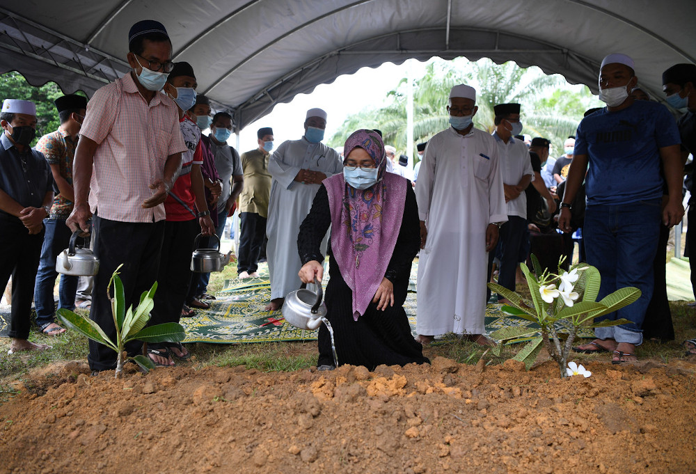 Balu Adun Chini Datin Seri Razana Fatin Abdullah, 46, menyiram air ke pusara suaminya. u00e2u20acu201d Foto Bernaman