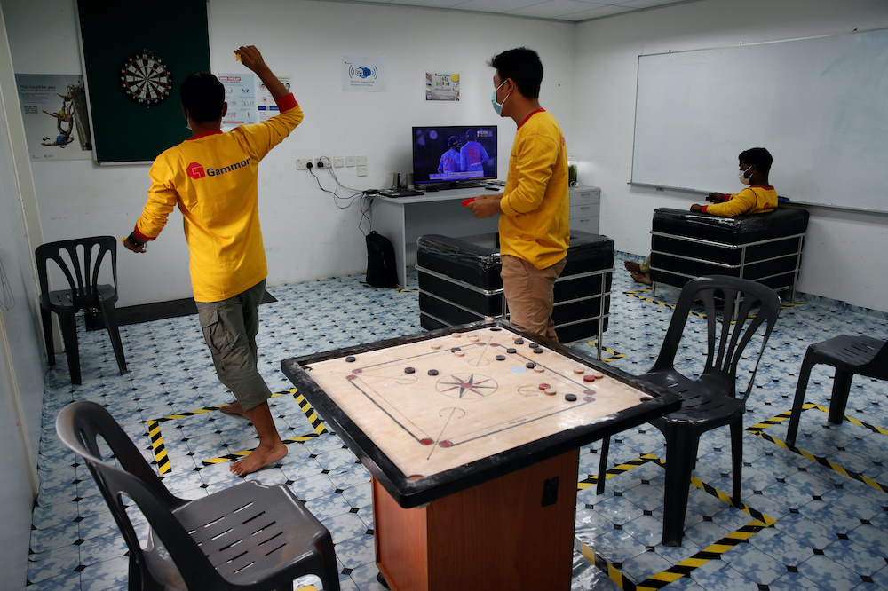 Migrant workers throw darts in a recreation room of their temporary living quarters for essential migrant workers at a train station construction site in Singapore May 5, 2020. u00e2u20acu201d Reuters pic nn