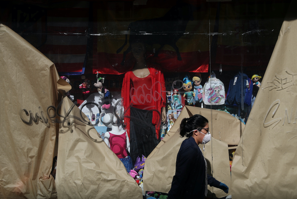 A woman wearing a protective face mask walks past a closed store displaying a Spanish flag, amid the coronavirus disease outbreak, in Madrid, Spain May 5, 2020. u00e2u20acu201d Reuters picnn