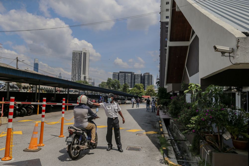 A security guard checks the temperature of a resident at the at Sri Angsana Hilir Condominium in Kuala Lumpur May 19, 2020. u00e2u20acu201d Picture by Firdaus Latif