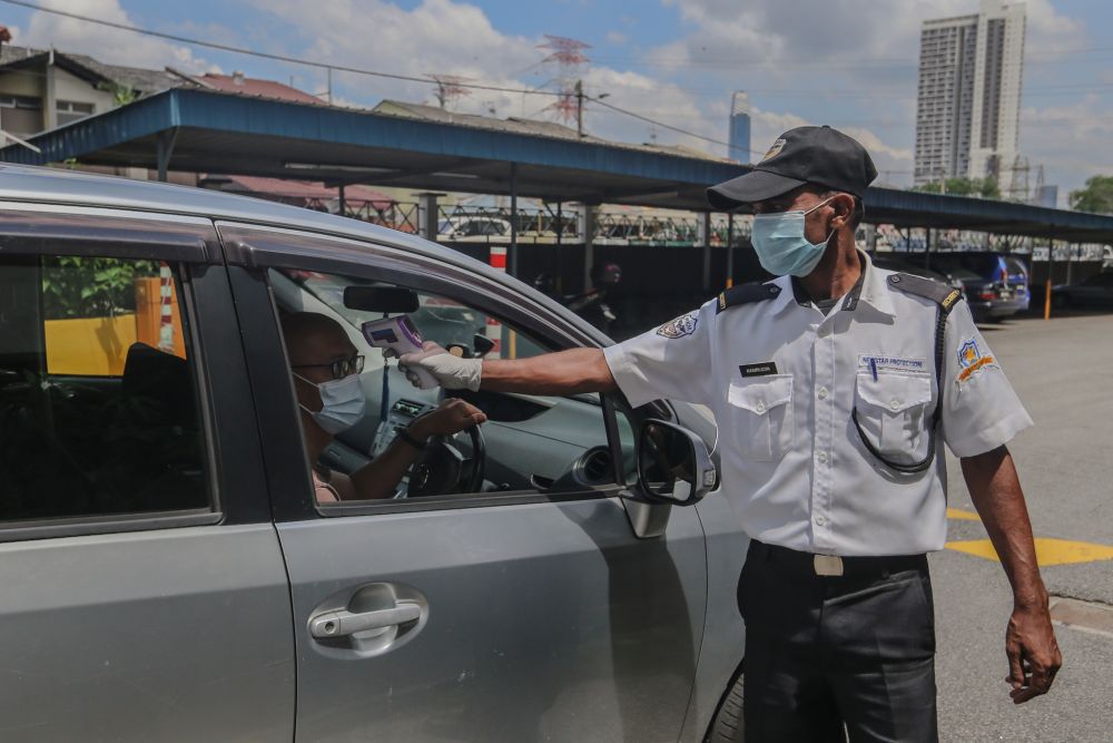 A security guard checks the temperature of a resident at the at Sri Angsana Hilir Condominium in Kuala Lumpur May 19, 2020. — Picture by Firdaus Latif