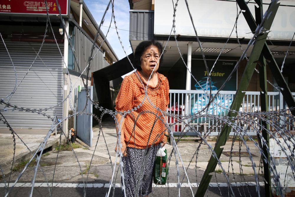 Retiree Wong Ai Kwok speaks to Malay Mail from beyond the barbed wire fencing at Petaling Jaya Old Town during the enhanced movement control order May 12, 2020. — Picture by Yusof Mat Isa