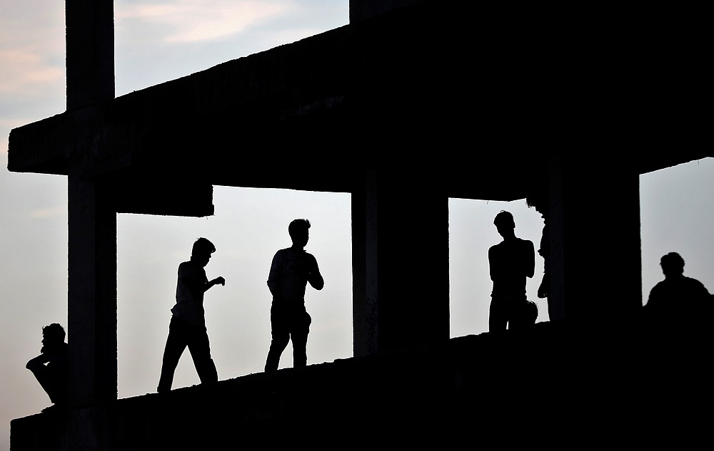 Migrant workers are silhouetted as they take shelter in a building under construction during an extended nationwide lockdown to slow Covid-19 in Ahmedabad, India, May 9, 2020. u00e2u20acu201d Reuters pic