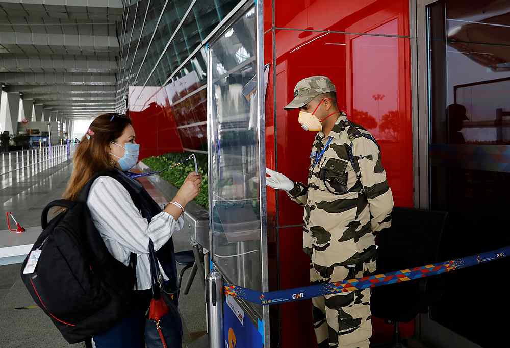 A member of the security force checks the ID of a woman through a glass shield, after the government allowed domestic flights to resume from May 25, 2020, at the New Delhi airport, India, May 23, 2020. u00e2u20acu201d Reuters pic 
