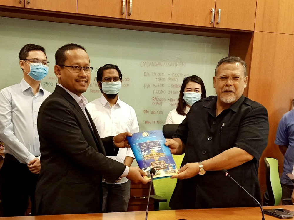 Johor Pakatan Harapan (PH) chief Aminolhuda Hassan (right) handing over the coalitionu00e2u20acu2122s assemblymen asset declaration to state legislative speaker Suhaizan Kayat in Iskandar Puteri May 31, 2020. u00e2u20acu201d Picture by Ben Tan