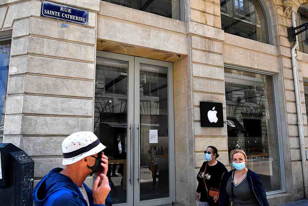 People wearing face mask walk by an Apple store. u00e2u20acu201d AFP pic