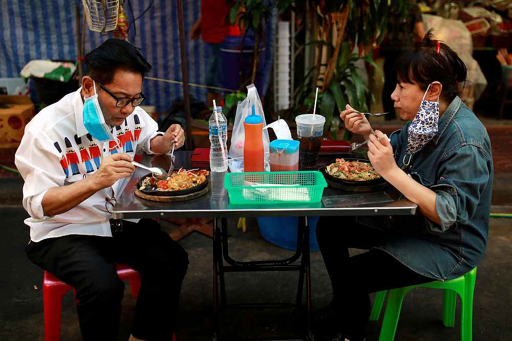 Customers' protective masks hang on their ears as they eat food in Chinatown, after the government started opening some restaurants outside shopping malls in Bangkok, Thailand, May 3, 2020. u00e2u20acu201d Reuters pic