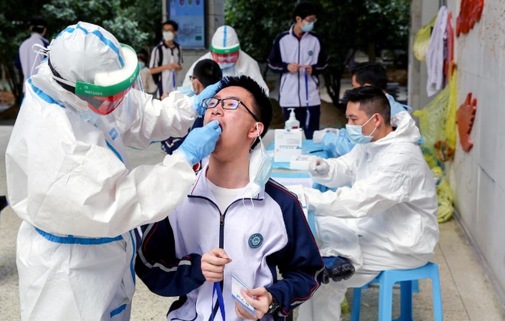 Workers in protective suits collect swabs from senior high school students for nucleic acid tests at Hubei Wuchang Experimental High School, in Wuhan, the Chinese city hit hardest by the Covid-19 disease outbreak, April 30, 2020. u00e2u20acu201d cnsphoto via Reuters