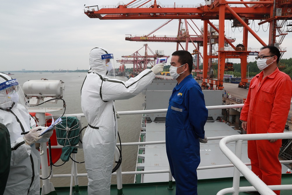 A staff member in protective suit takes body temperature measurement of a crew worker of a cargo ship bound for Japan at a container terminal at a port in Wuhan, Hubei province May 9, 2020. u00e2u20acu2022 Handout via Reuters
