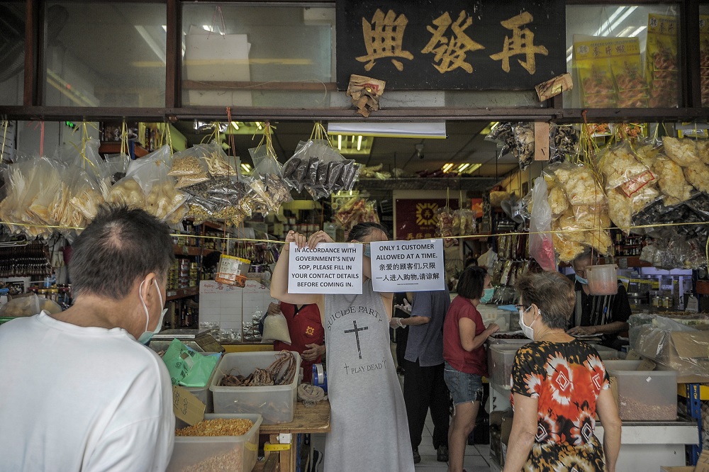 A worker hangs up a notice detailing new standard operating procedures during the conditional movement control at a Chinese sundry shop in Kuala Lumpur May 4, 2020. ― Picture by Shafwan Zaidon