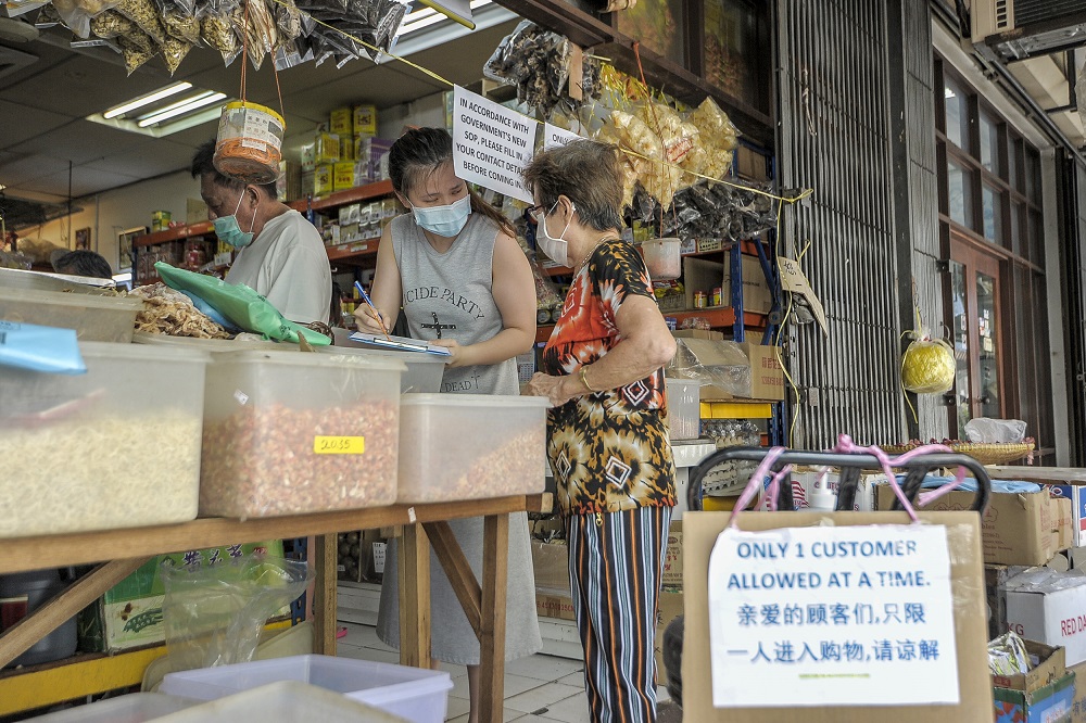 A worker at a Chinese sundry shop collects customers' details as part of new standard operating procedures during the conditional movement control in Kuala Lumpur May 4, 2020. u00e2u20acu2022 Picture by Shafwan Zaidon
