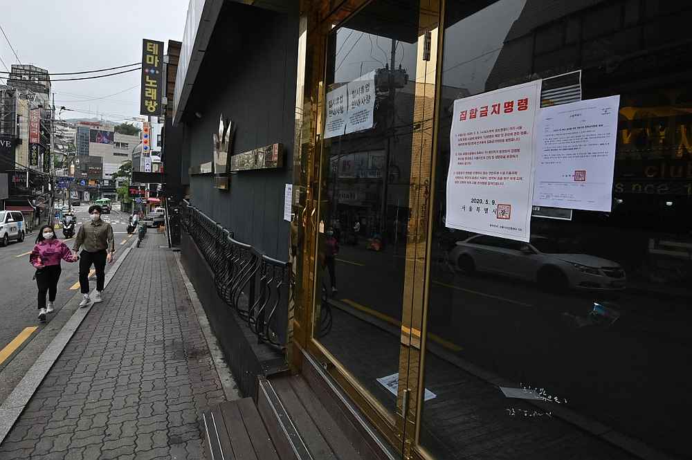 A couple wearing face masks walk past a night club, now closed following a visit by a confirmed Covid-19 patient, in the popular nightlife district of Itaewon, Seoul, South Korea on May 10, 2020. u00e2u20acu201d AFP pic