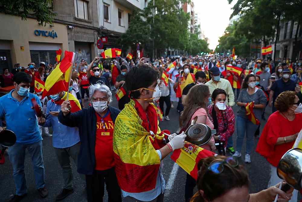 People wearing protective face masks bang saucepans and carry Spanish flags as they attend a protest against the Spanish government's handling of the Covid-19 crisis, in Madrid May 18, 2020. u00e2u20acu201d Reuters pic