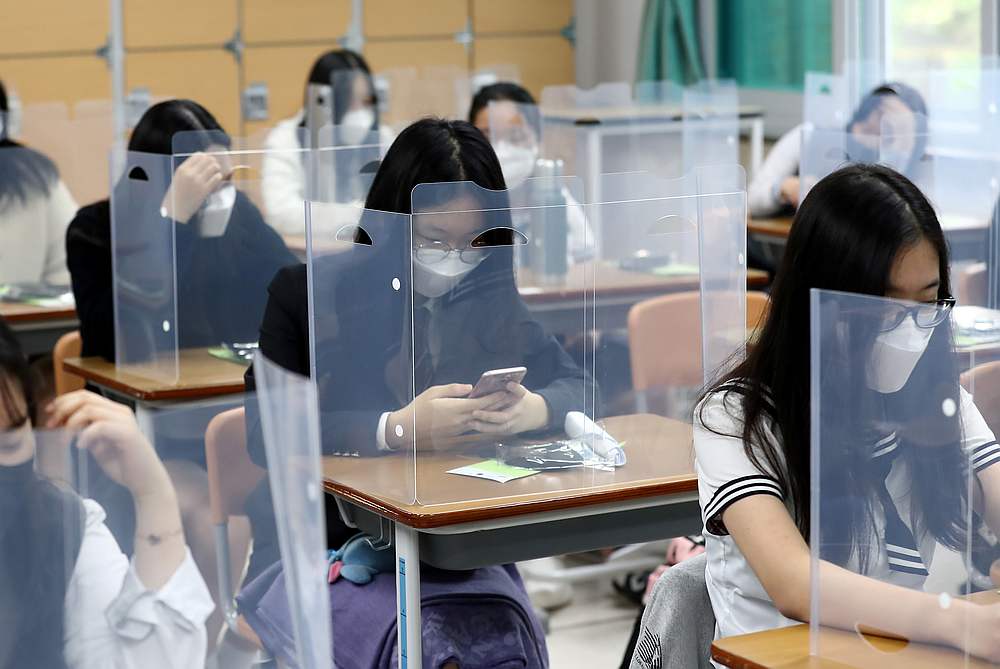High school students wearing face masks prepare for classes, with plastic covers placed on desks to prevent infection, in Daejeon, South Korea May 20, 2020. u00e2u20acu201d Yonhap pic via Reuters 