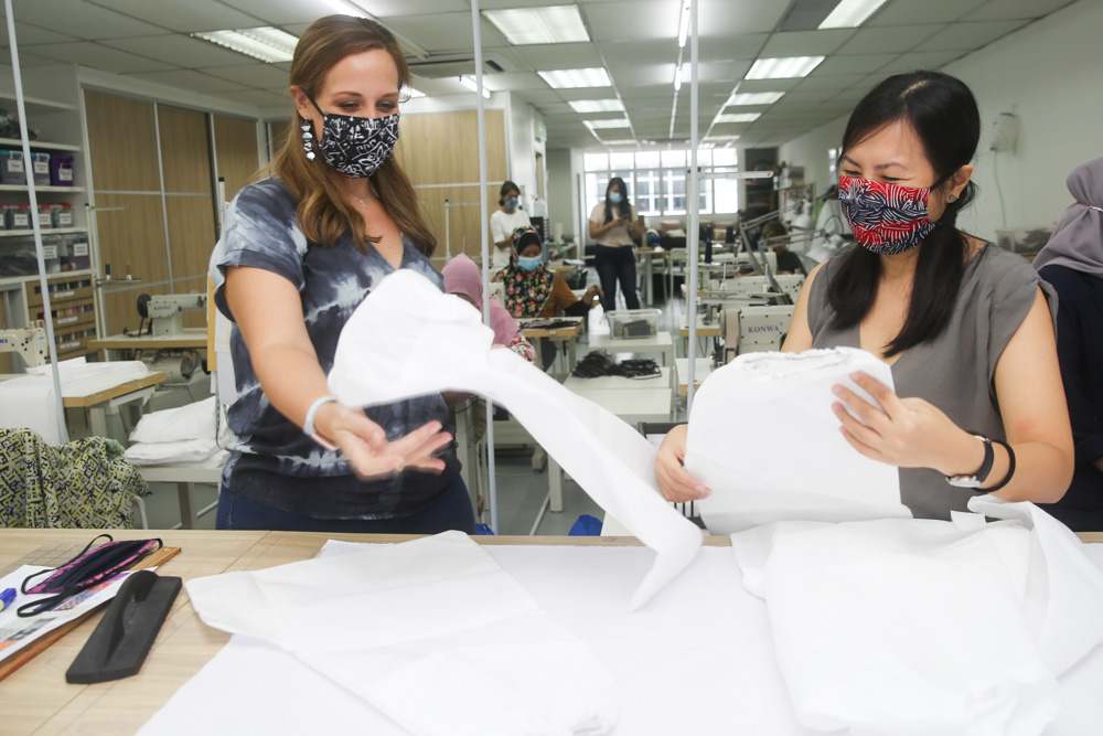 Blair (left) and AirAsia Foundation executive director Yap Mun Ching showing the hospital-grade material used to produce the PPE. — Picture by Choo Choy May