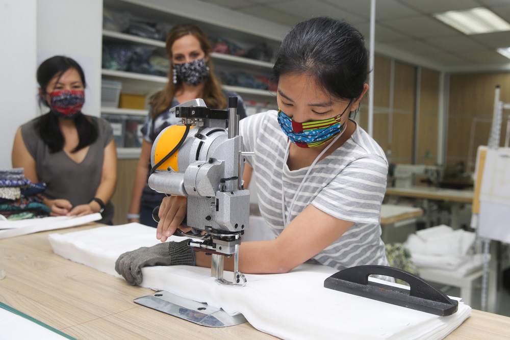 Batik Boutique production manager Kylin Kwan operating machinery to cut material for the PPE sets. — Picture by Choo Choy May