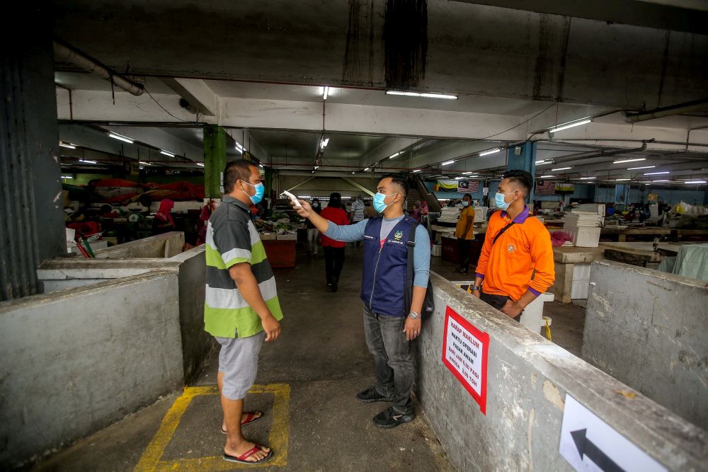 An enforcement officer from the Ipoh City Council conducts temperature checks at Pasar Besar Ipoh on the first day of the conditional movement control order May 4, 2020. u00e2u20acu201d Picture by Farhan Najib