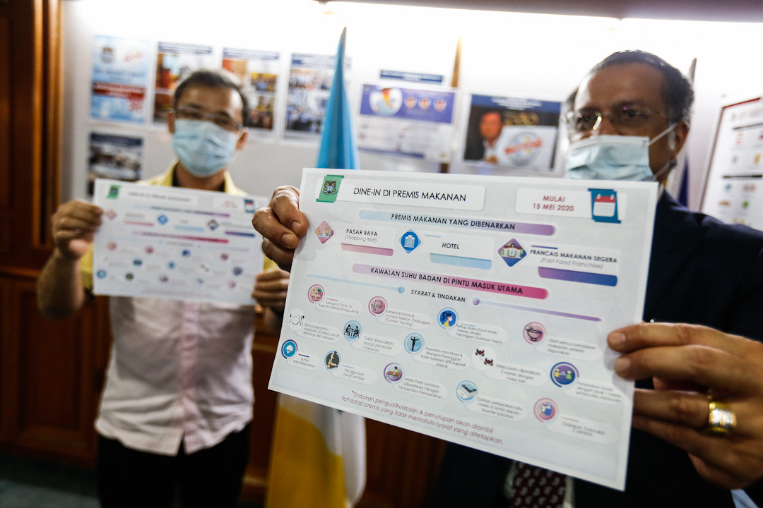 Penang exco Jagdeep Singh Deo (right) and mayor Datuk Yew Tung Seang hold up a copy of the new SOP for restaurant operators during a press conference at Komtar, George Town May 13, 2020. u00e2u20acu201d Picture by Sayuti Zainudin