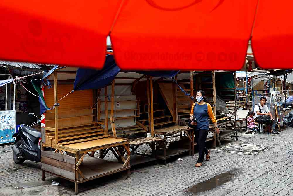 A woman wearing a protective face mask walks past closed street vendors booths at a traditional market in Jakarta, Indonesia May 4, 2020. u00e2u20acu201d Reuters pic 