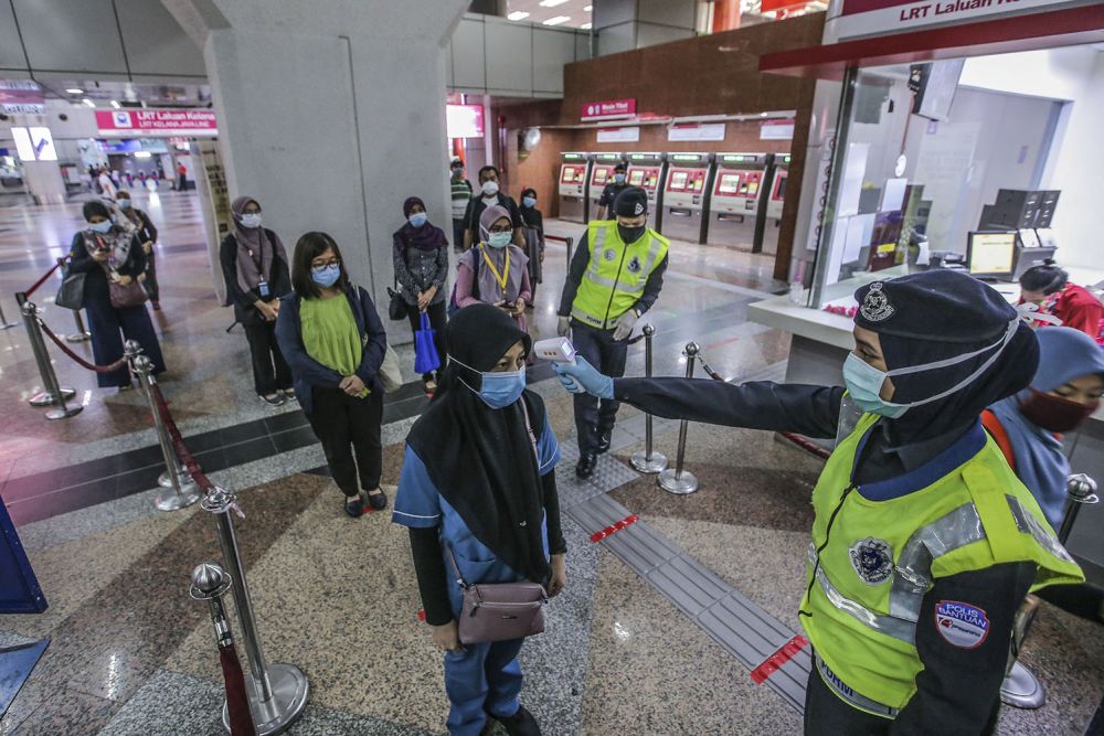 Commuters have their temperature checked at the KL Sentral LRT station on Day One of the conditional movement control order in Kuala Lumpur May 4, 2020. — Picture by Hari Anggara