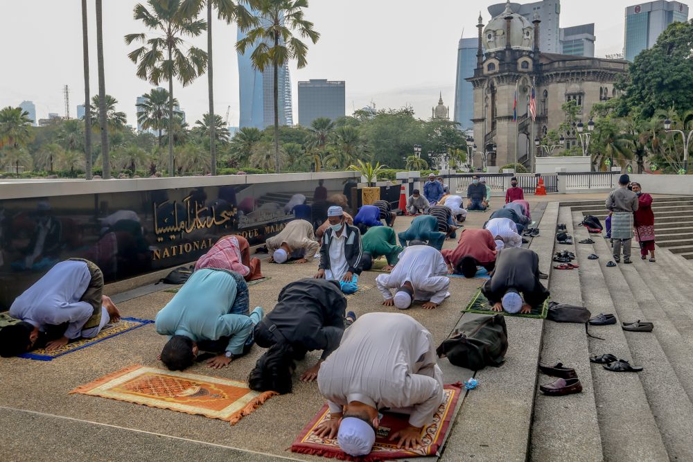 Muslims perform Eid Al-Fitr prayers outside the National Mosque before being told to leave by the police in Kuala Lumpur May 24, 2020 — Picture by Firdaus Latif