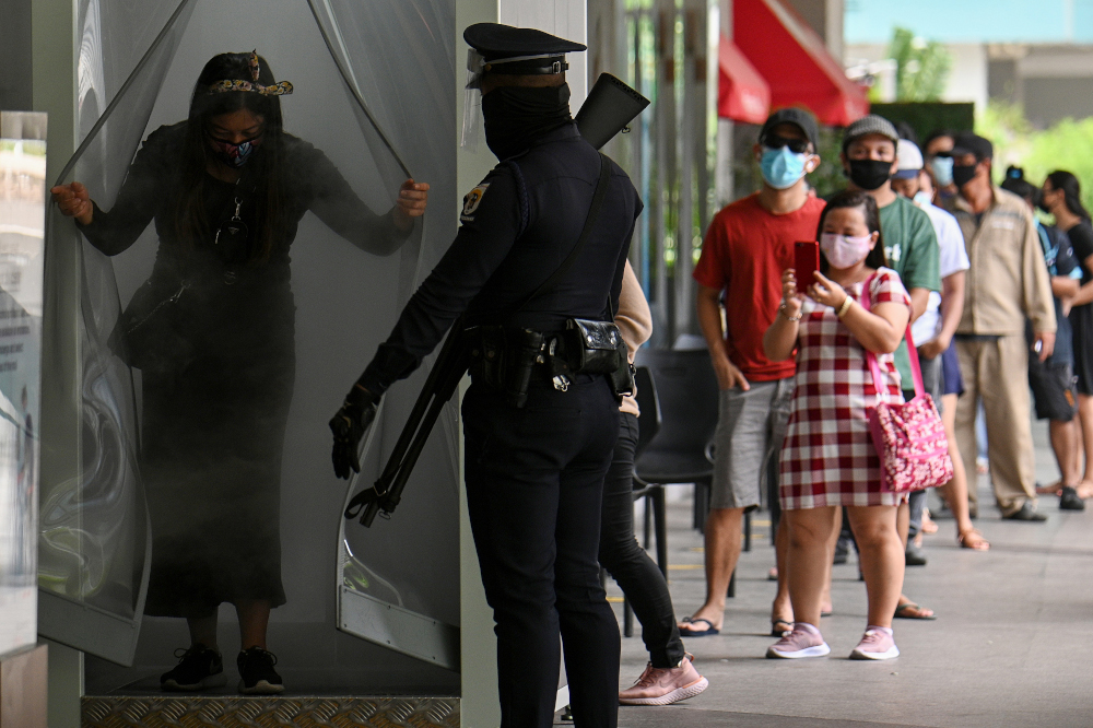 A security guard watches as a shopper exits from a disinfection channel installed at the entrance of a shopping mall as a preventive measure against the Covid-19 coronavirus, in Manila May 16, 2020. u00e2u20acu201d AFP pic 
