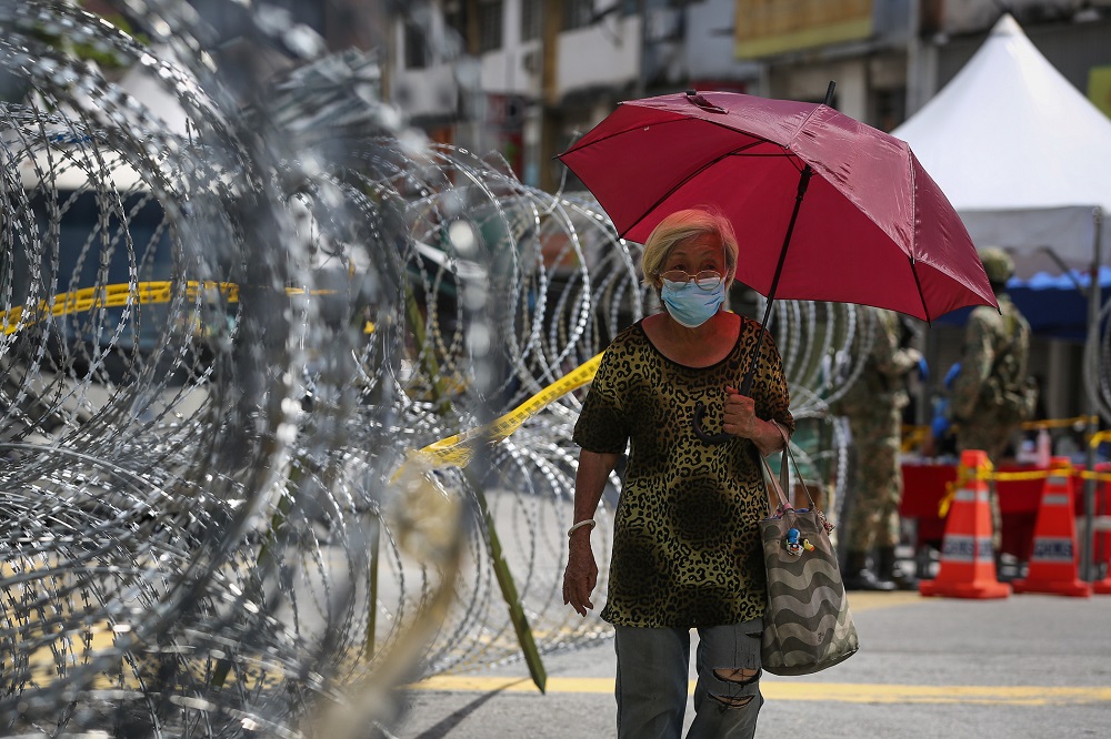 A woman walks past barbed wire fencing in Pudu, Kuala Lumpur May 19, 2020. u00e2u20acu2022 Picture by Yusof Mat Isa
