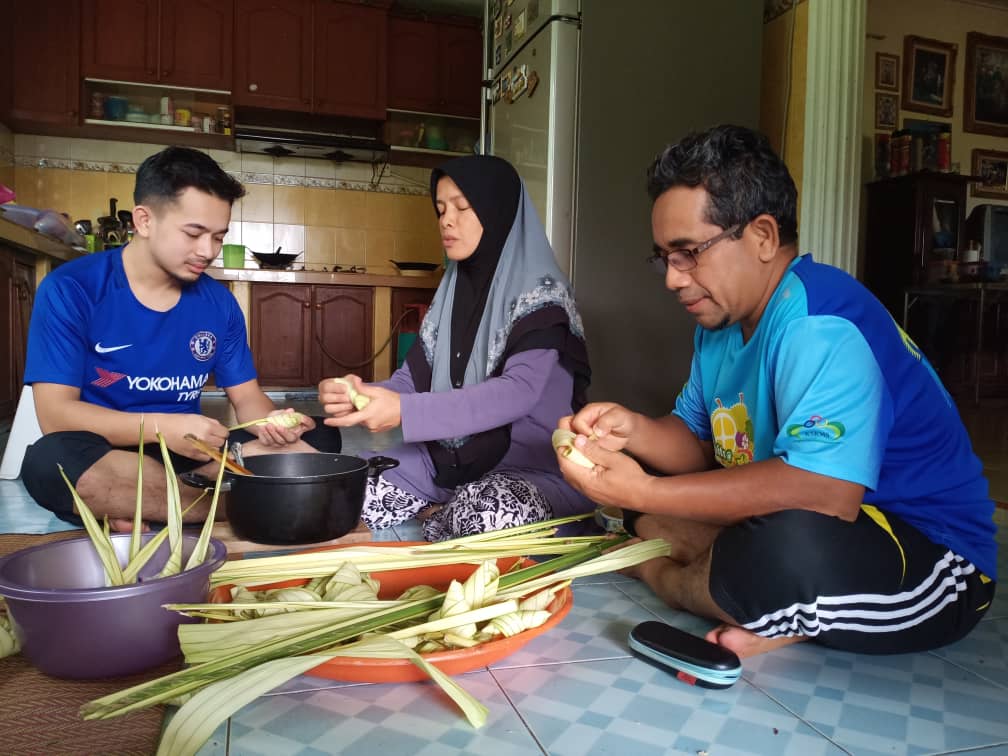 Mohd Sobri Mohd Noor (right) making ketupat with his wife Nor Aslin Jaafar and son Muhammad Najmi Mohd Sobri.