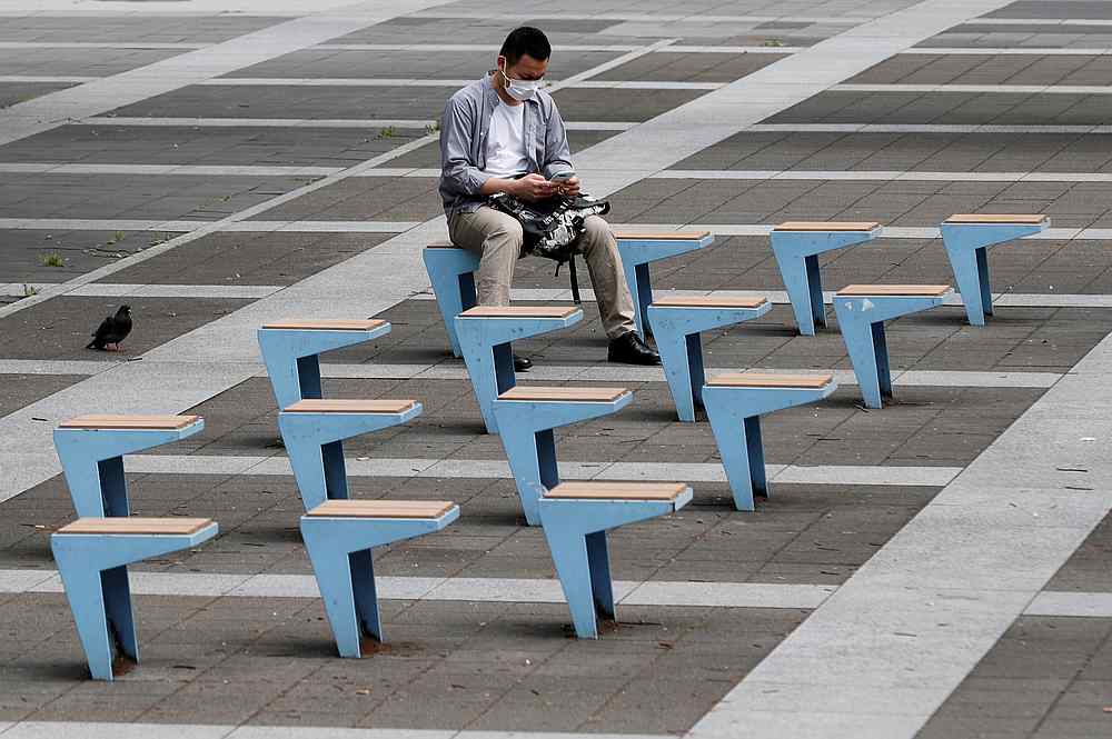 A man wearing a protective mask uses a cellphone as he sits on a bench near Shinagawa station on the first day after the Japanese government lifted the state of emergency in Tokyo, Japan, May 26, 2020. u00e2u20acu201d Reuters pic