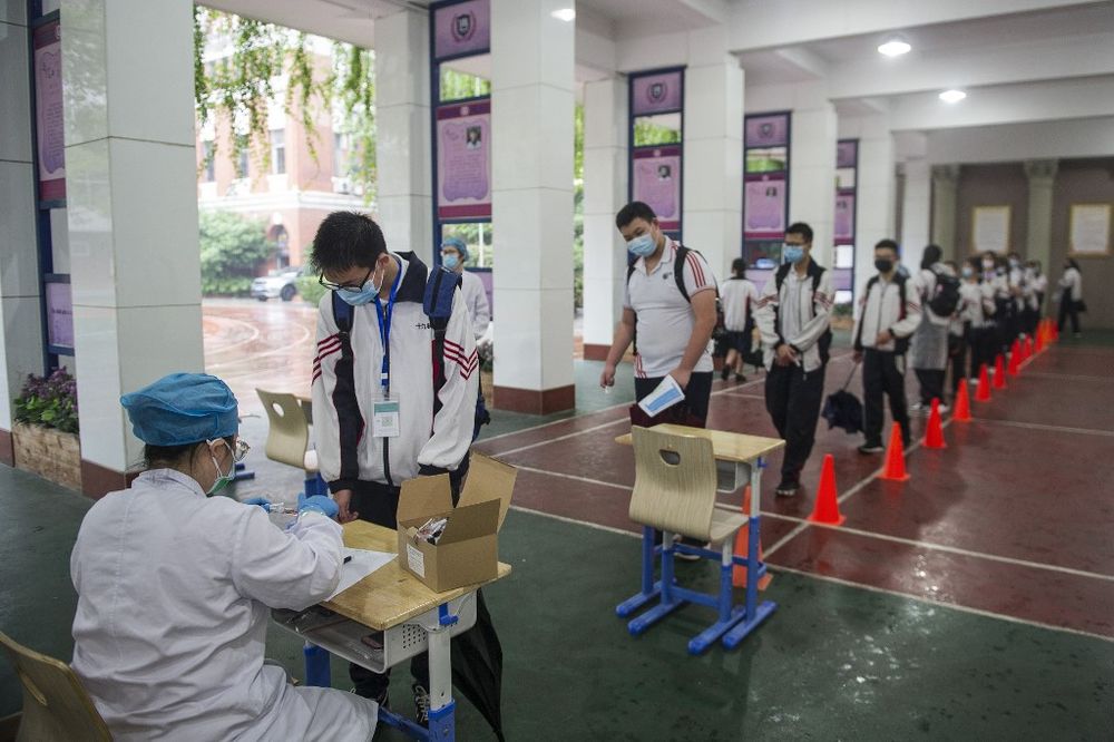 A medical worker (left) prepares to take a swab sample from a student to be tested for the Covid-19 novel coronavirus as senior students prepare to return to school in Wuhan in Chinau00e2u20acu2122s central Hubei province, May 14, 2020. u00e2u20acu201d AFP pic