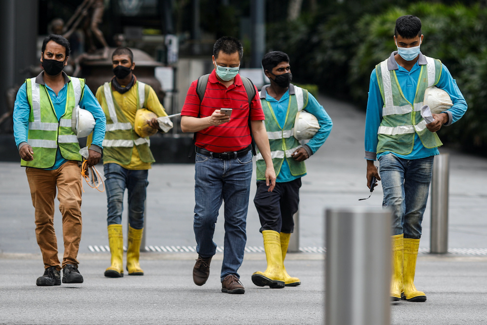 Migrant workers in essential services wearing safety vests cross a street at Orchard Road, amid the coronavirus disease (Covid-19) outbreak in Singapore, May 27, 2020. u00e2u20acu201d Reuters pic