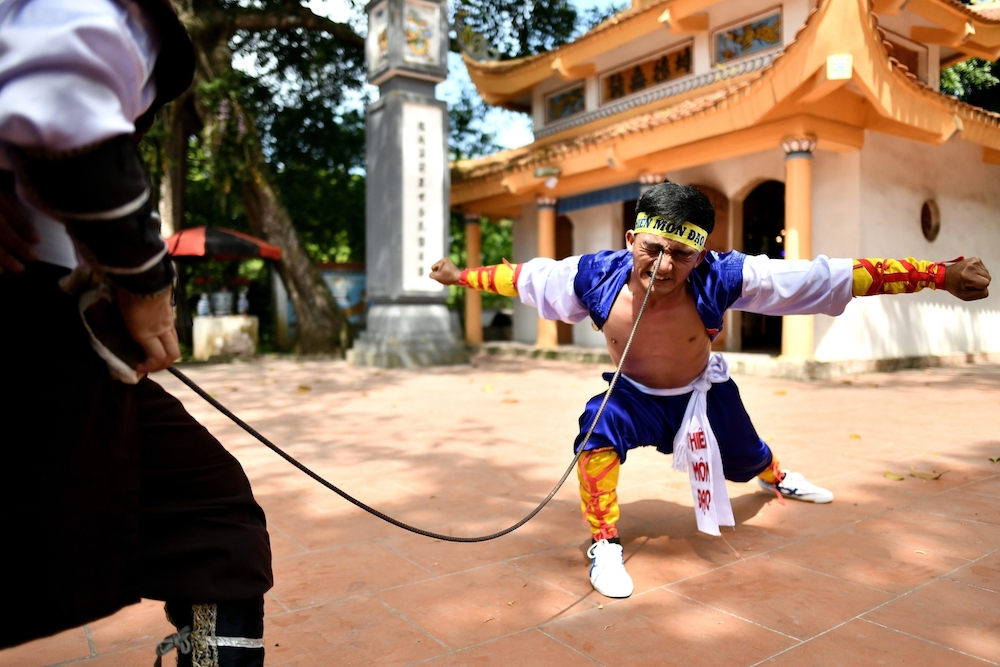 Le Van Thang, 28, student of the centuries-old martial art of Thien Mon Dao, bending a construction rebar against his eye socket inside the Bach Linh temple. u00e2u20acu201d AFP pic