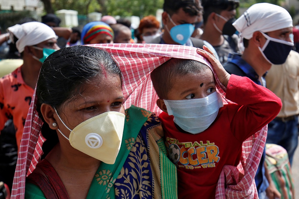 A migrant worker covers her child with a scarf to protect it from the heat, as they wait to get on a bus for a railway station in Ahmedabad June 5, 2020. u00e2u20acu201d Reuters pic