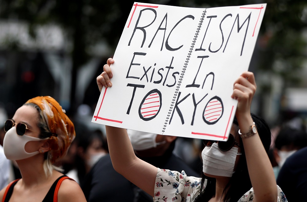 A demonstrator wearing a mask holds a placard during a protest march over the alleged police abuse of a Turkish man, in Tokyo June 6, 2020. — Reuters pic