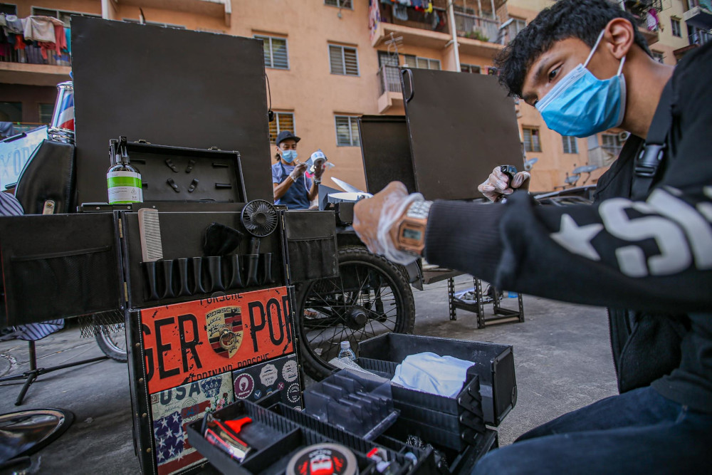 Genttouch Barbershop workers Muhammad Aidilfikri Zahari (left) and Mohd Shahrin Saimin (centre) demonstrate how to clean one's tools as per standard operating procedures in Ampang June 7, 2020. — Picture by Hari Anggara