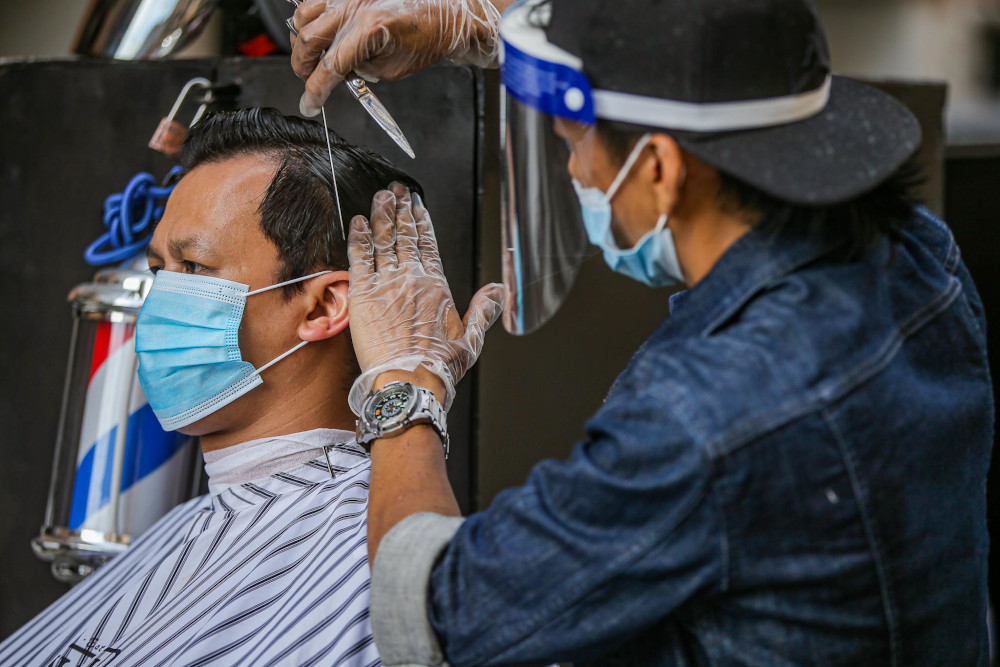 Genttouch Barbershop's Mohd Shahrin Saimin gives a demonstration of the standard operating procedures for barbers in Ampang June 7, 2020. u00e2u20acu201d Picture by Hari Anggara