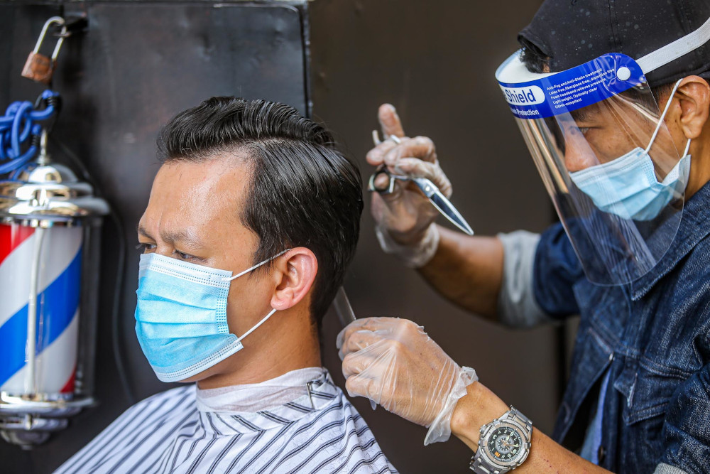 Genttouch Barbershop's Mohd Shahrin Saimin gives a demonstration of the standard operating procedures for barbers in Ampang June 7, 2020. u00e2u20acu201d Picture by Hari Anggara
