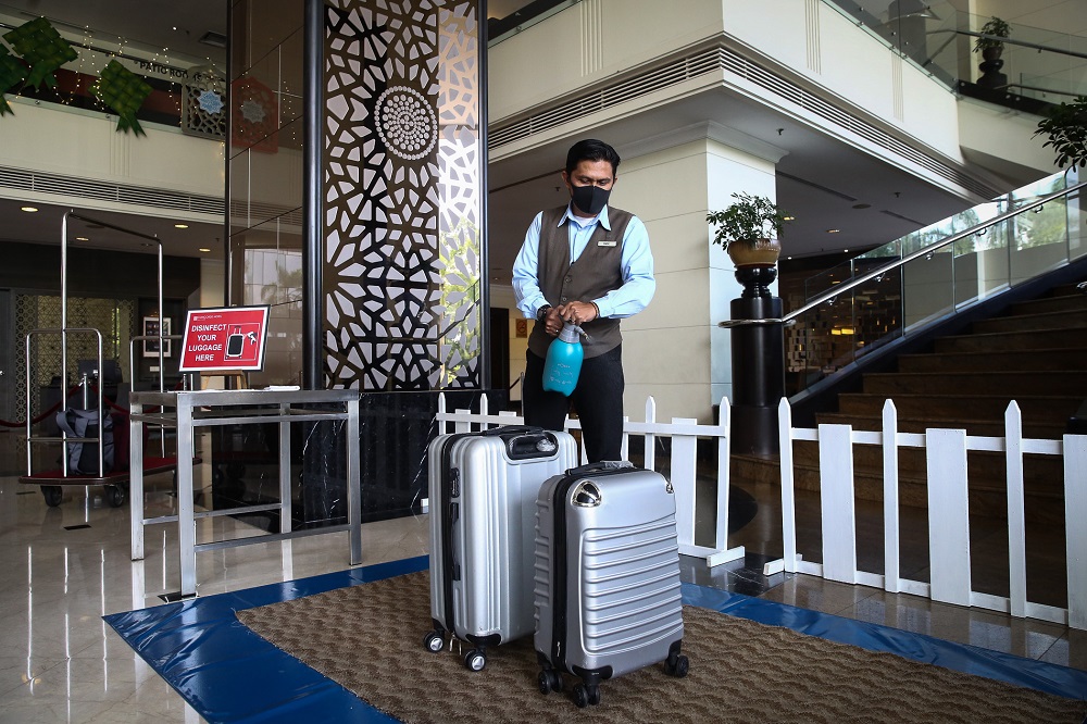 A hotel staff disinfects guests' luggage at the lobby of the Concorde Hotel in Shah Alam June 9, 2020. — Picture by Yusof Mat Isa
