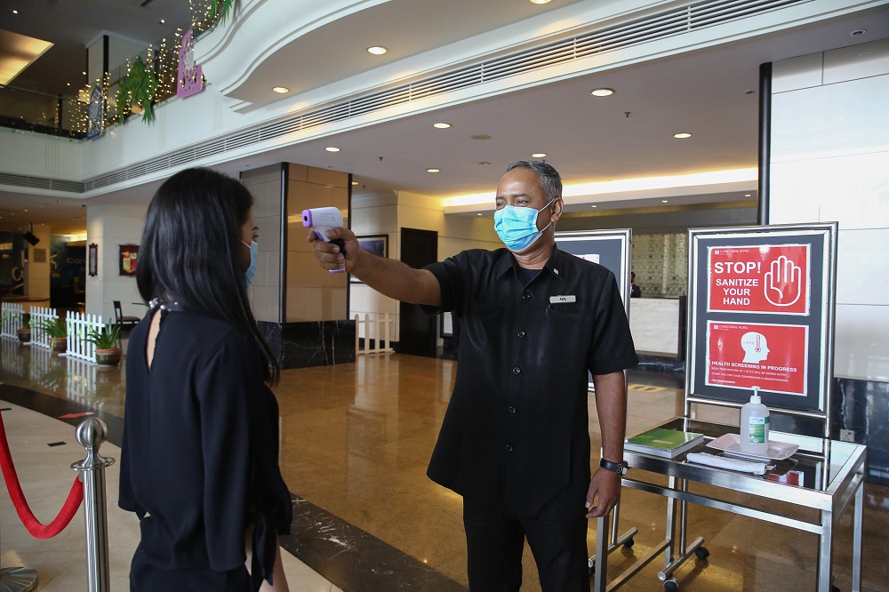 A hotel employee checks the temperature of a guest at the lobby of the Concorde Hotel in Shah Alam June 9, 2020. u00e2u20acu201d Picture by Yusof Mat Isa