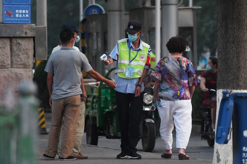 A worker takes the temperature of people walking outside the Xinfadi meat wholesale market in Beijing June 12, 2020. u00e2u20acu201d AFP pic